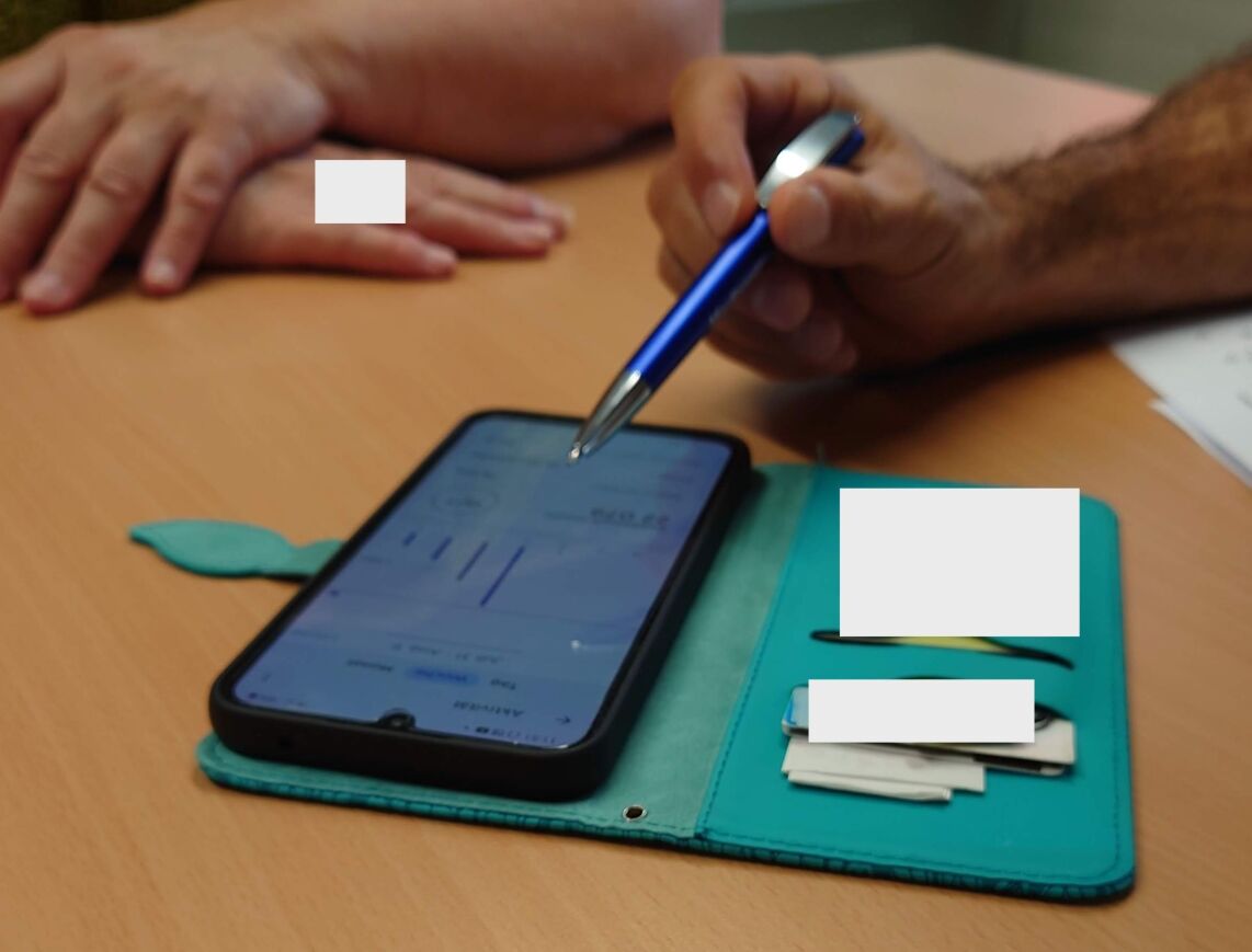 Photograph of a consultation where a participant and a healthcare professional view health data on a smartphone.