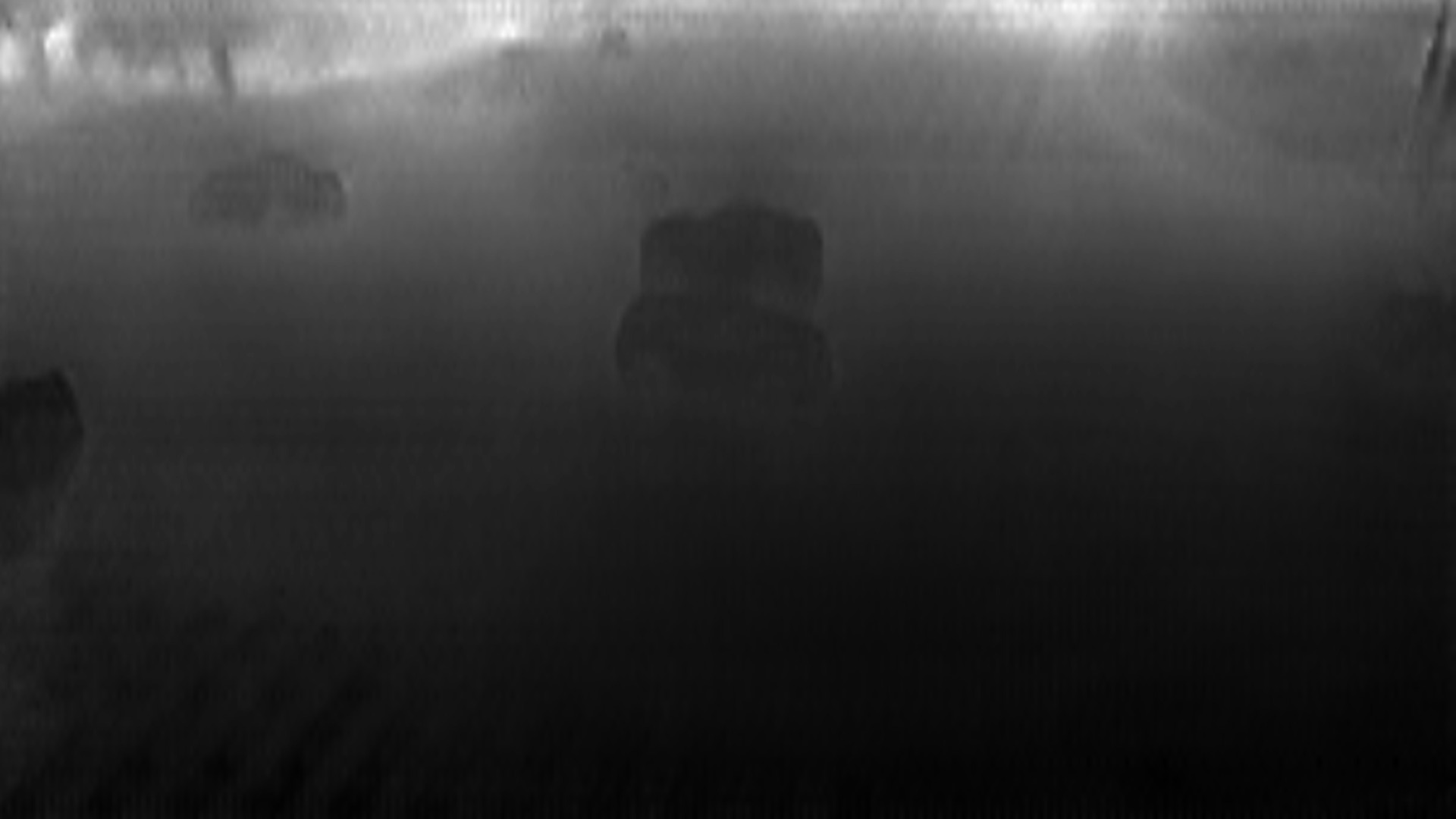 Black and White Depth estimation map of urban intersection with cars navigating through a multi-lane crossing.