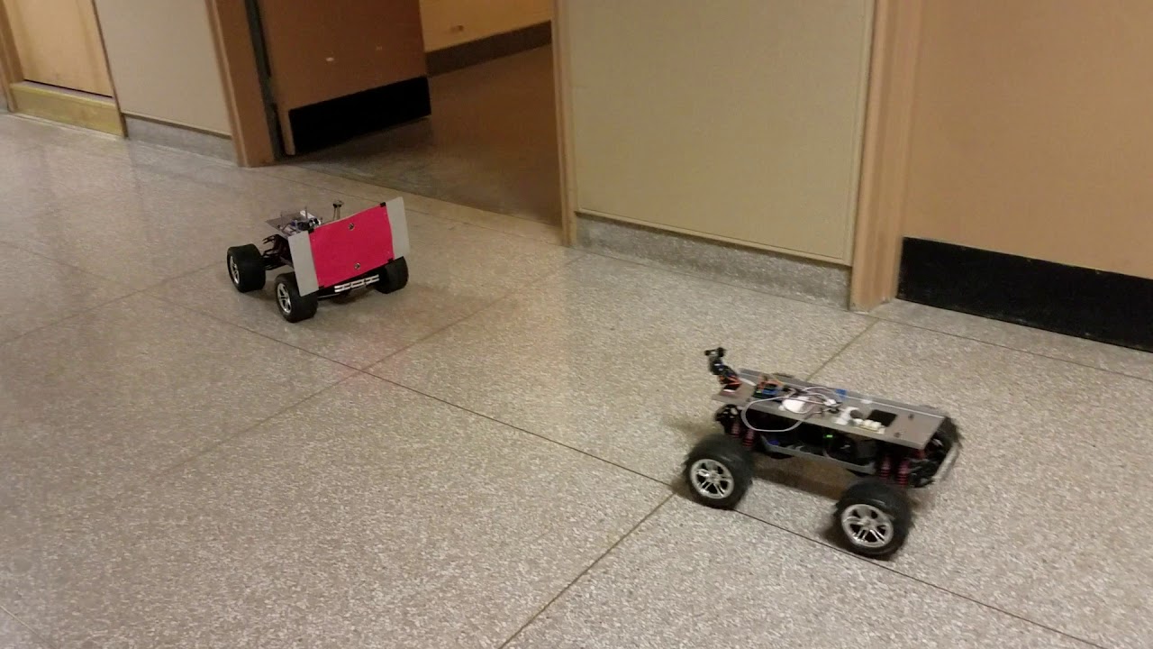 A leader-follower robot pair navigates a hallway, with the follower utilizing a front-mounted camera to track a readily-identifiable <span class="katex-eq" data-katex-display="false">	ext{red}</span> target on the leader for coordinated movement.